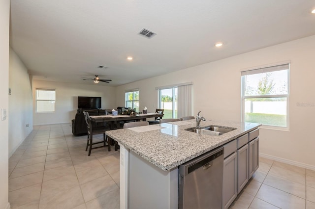 kitchen with ceiling fan, sink, light tile patterned floors, dishwasher, and an island with sink