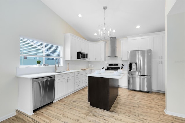 kitchen featuring pendant lighting, white cabinets, appliances with stainless steel finishes, a center island, and wall chimney exhaust hood