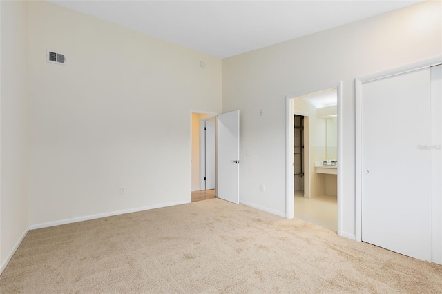 unfurnished bedroom with a closet, ensuite bathroom, and carpet