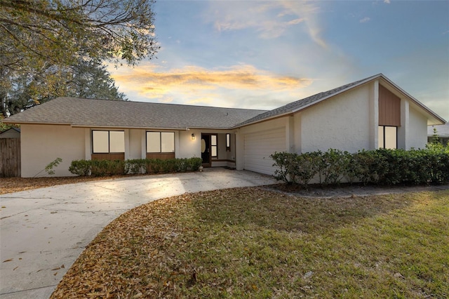 ranch-style house featuring a garage and a lawn