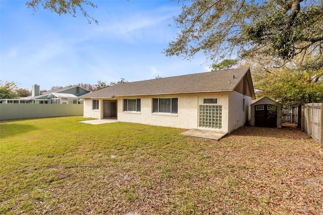 back of house featuring a lawn, a storage shed, and a patio