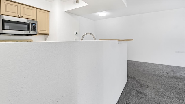 kitchen featuring dark colored carpet and light brown cabinetry