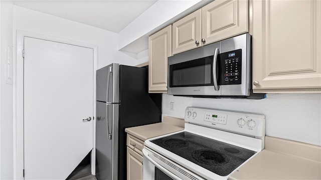 kitchen featuring cream cabinets, stainless steel appliances, and hardwood / wood-style flooring