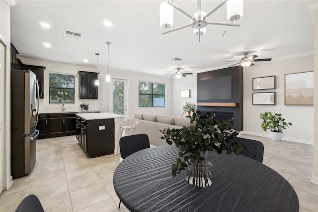 dining space with ceiling fan, sink, light tile patterned floors, and crown molding