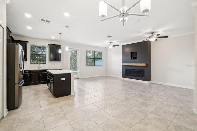 kitchen featuring stainless steel refrigerator with ice dispenser, ornamental molding, pendant lighting, a fireplace, and a center island