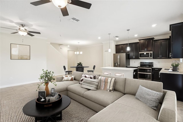 tiled living room featuring ceiling fan with notable chandelier and crown molding