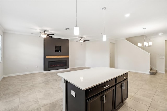 kitchen with pendant lighting, a kitchen island, crown molding, and a fireplace