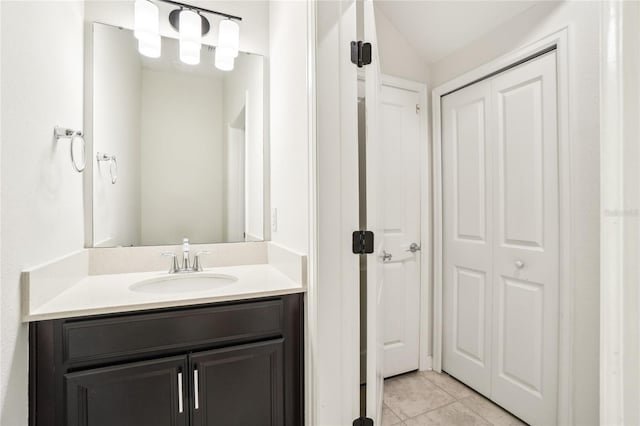 bathroom featuring tile patterned floors, vanity, and vaulted ceiling