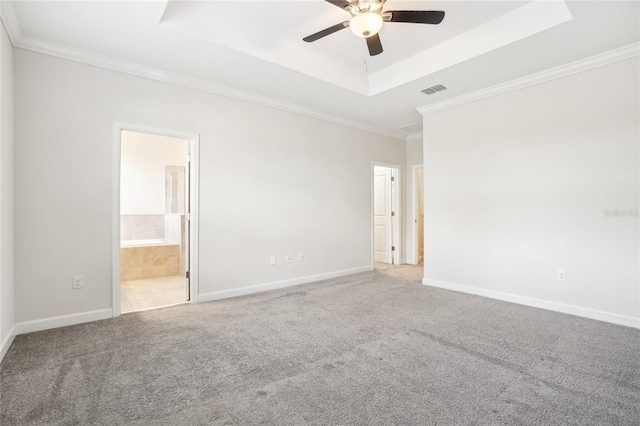 carpeted spare room with ceiling fan, ornamental molding, and a tray ceiling