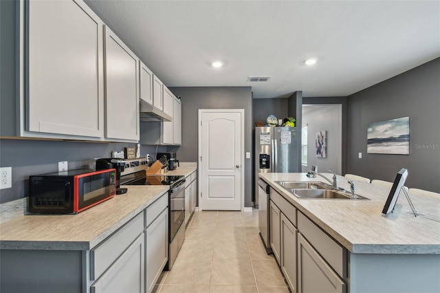 kitchen featuring sink, stainless steel appliances, an island with sink, gray cabinets, and light tile patterned floors