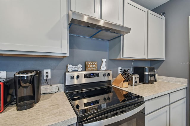 kitchen featuring stainless steel electric range and white cabinetry