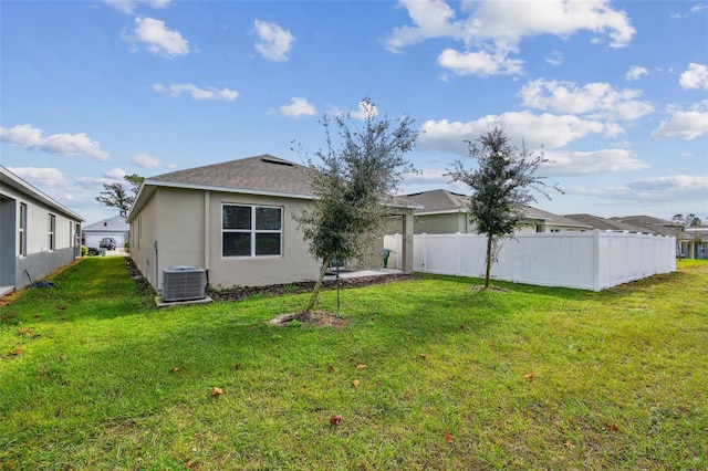 rear view of property featuring a lawn and central AC