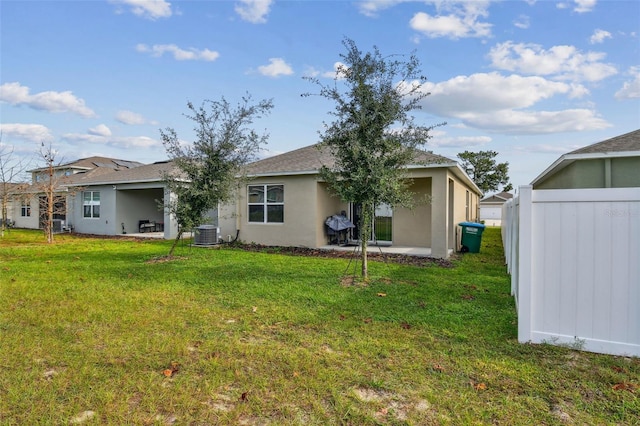 rear view of property featuring a lawn, a patio area, and cooling unit