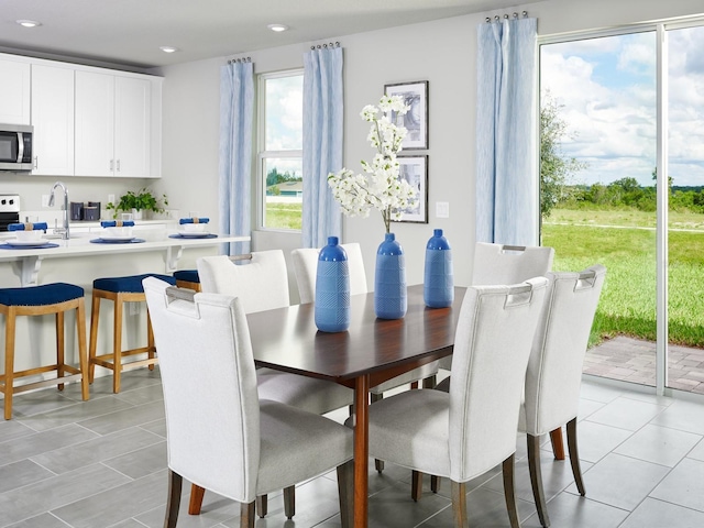 dining area featuring a wealth of natural light, sink, and light tile patterned flooring