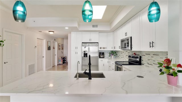 kitchen with appliances with stainless steel finishes, white cabinets, visible vents, and ornamental molding