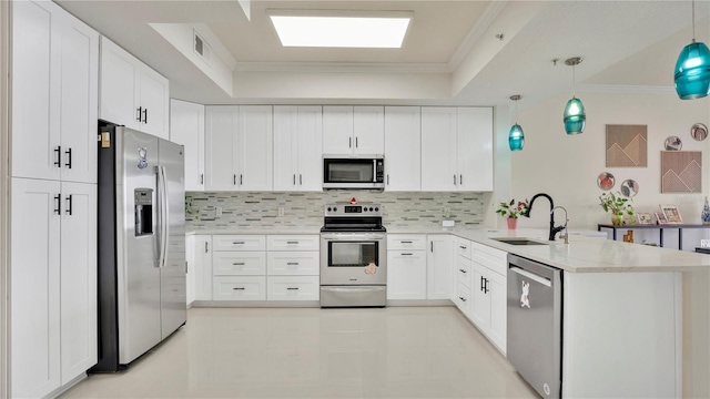 kitchen with decorative light fixtures, a peninsula, stainless steel appliances, white cabinetry, and a sink