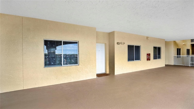 interior space featuring carpet, a textured ceiling, and a textured wall