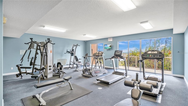 gym featuring a textured ceiling and baseboards