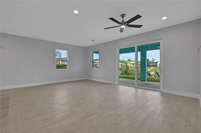 empty room with ceiling fan, a healthy amount of sunlight, and light hardwood / wood-style flooring