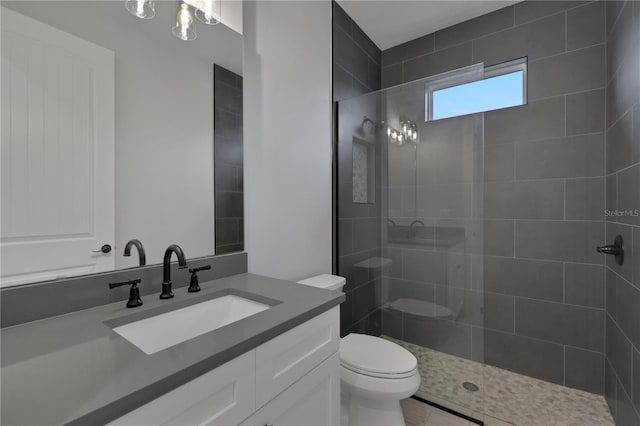 bathroom featuring tiled shower, vanity, toilet, and tile patterned flooring