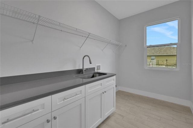 clothes washing area with light hardwood / wood-style floors, cabinets, sink, and hookup for a washing machine