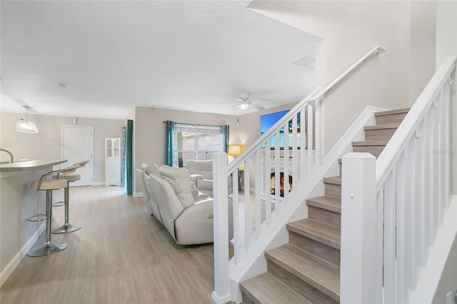 staircase featuring hardwood / wood-style flooring, ceiling fan, and a textured ceiling