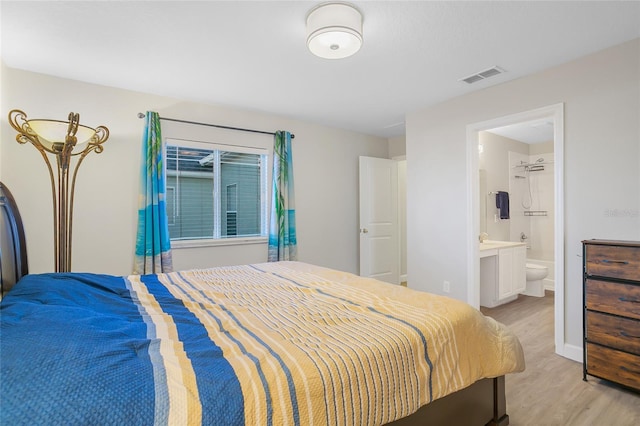 bedroom featuring connected bathroom and light hardwood / wood-style floors