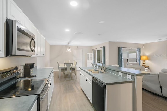 kitchen featuring stainless steel appliances, a kitchen island with sink, sink, light hardwood / wood-style flooring, and white cabinetry