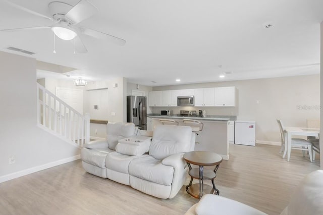 living room with light hardwood / wood-style floors and ceiling fan