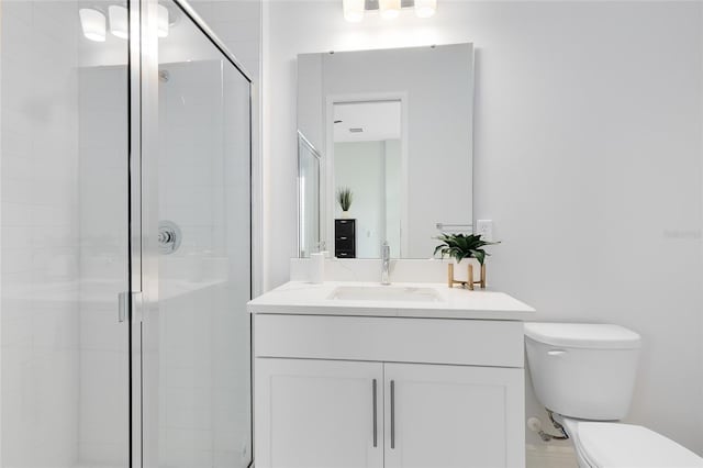 bathroom featuring toilet, a shower with door, and vanity