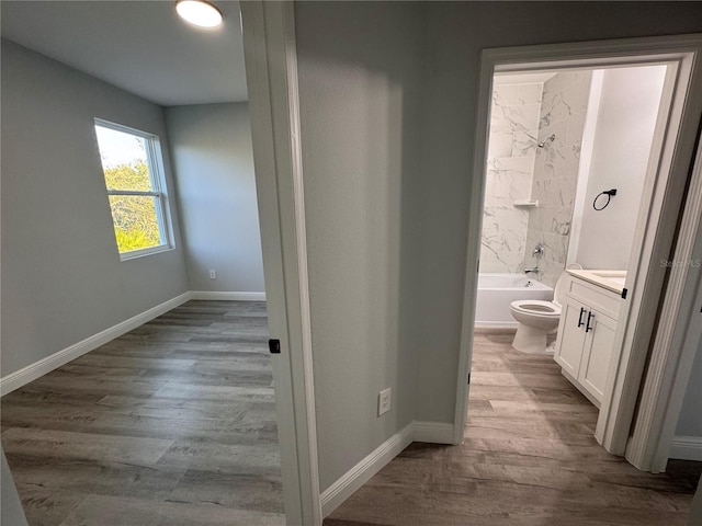 full bathroom with tiled shower / bath, vanity, wood-type flooring, and toilet