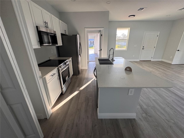 kitchen featuring sink, dark wood-type flooring, a kitchen island with sink, white cabinets, and appliances with stainless steel finishes