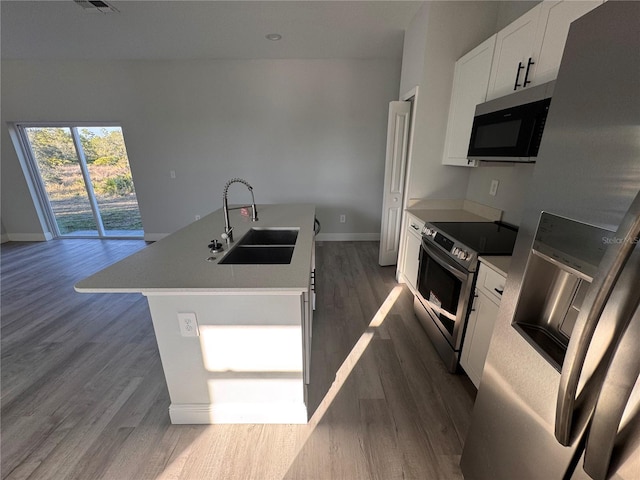 kitchen with appliances with stainless steel finishes, dark hardwood / wood-style flooring, sink, a center island with sink, and white cabinetry