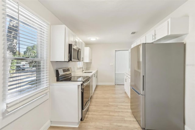 kitchen with sink, white cabinets, stainless steel appliances, and light hardwood / wood-style floors