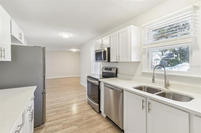 kitchen with stainless steel appliances, white cabinetry, light hardwood / wood-style floors, and sink