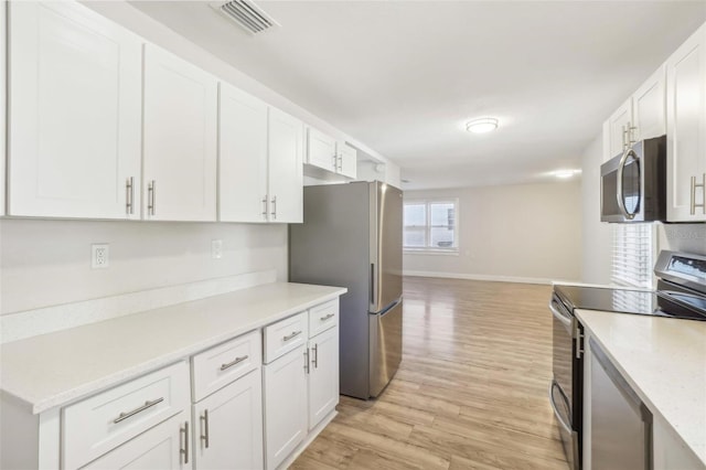 kitchen with appliances with stainless steel finishes, light wood-type flooring, and white cabinetry