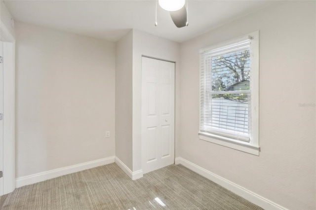 unfurnished bedroom featuring ceiling fan, light colored carpet, and a closet