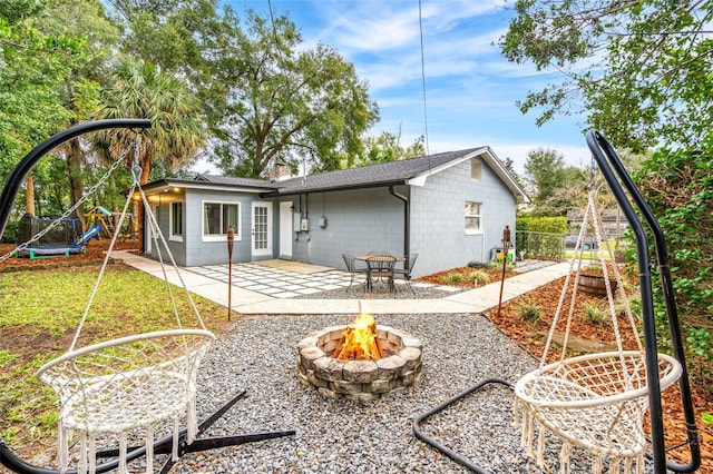 back of property with a patio area, a fire pit, and a trampoline