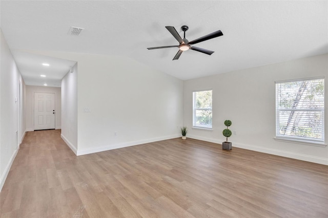 empty room with ceiling fan, lofted ceiling, and light hardwood / wood-style floors