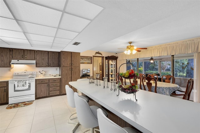 kitchen featuring a paneled ceiling, white electric range, ceiling fan, light tile patterned floors, and dark brown cabinetry