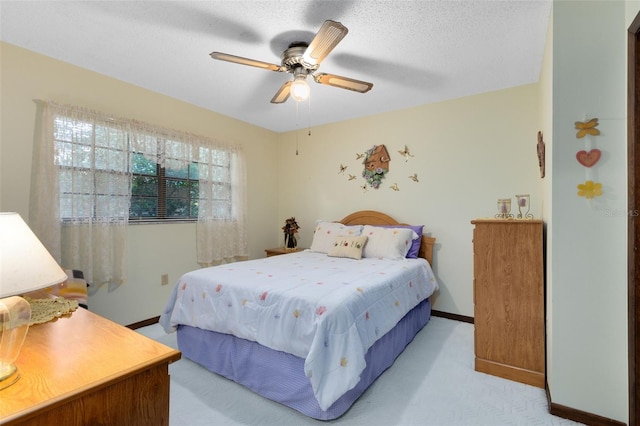 carpeted bedroom with ceiling fan and a textured ceiling