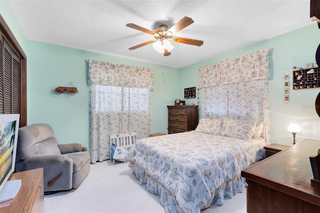 bedroom with ceiling fan, a textured ceiling, and light carpet