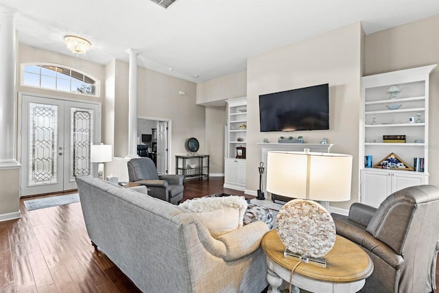 living room featuring dark hardwood / wood-style flooring, decorative columns, and french doors