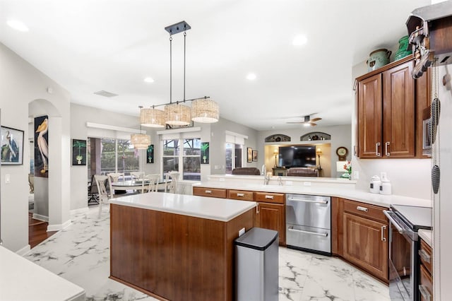 kitchen featuring kitchen peninsula, stainless steel appliances, ceiling fan, a kitchen island, and hanging light fixtures