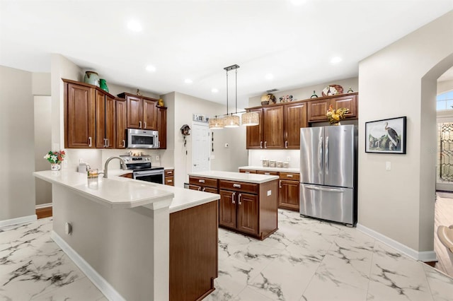 kitchen with a center island, sink, appliances with stainless steel finishes, decorative light fixtures, and kitchen peninsula