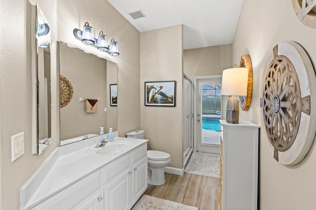 bathroom featuring hardwood / wood-style flooring, vanity, toilet, and a shower