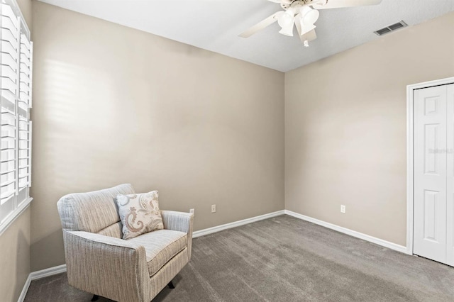 sitting room with dark carpet, ceiling fan, and a healthy amount of sunlight