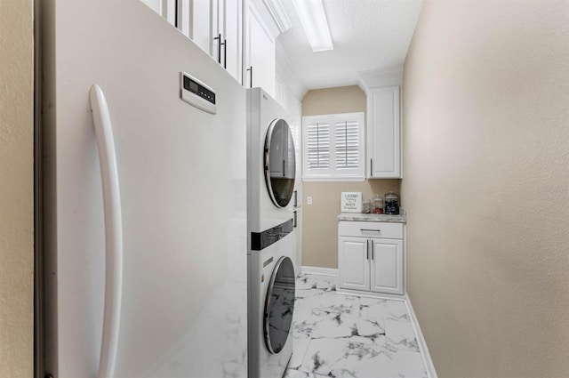 laundry room with stacked washer / dryer and cabinets