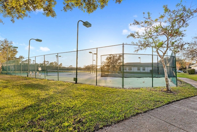 view of tennis court with a yard