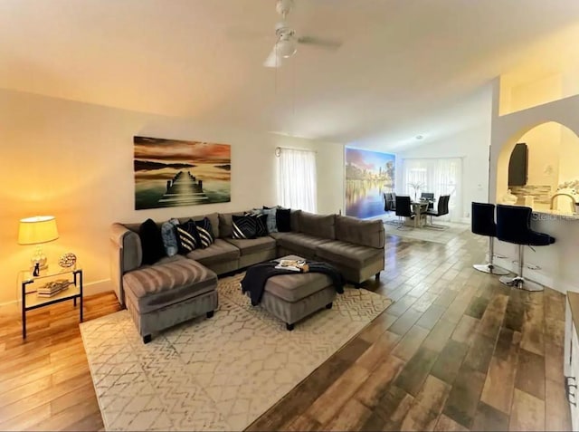 living room with light hardwood / wood-style floors, vaulted ceiling, ceiling fan, and sink